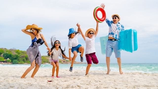Happy Asian family enjoying summer vacation on the beach